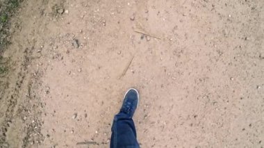 Erkek bacakları yere basıyor ve dışarıda bir sürü çöp var. Kot pantolonlu ve spor ayakkabılı bir adam kirli bir yere geliyor ve arka planda bir sürü çöp var..
