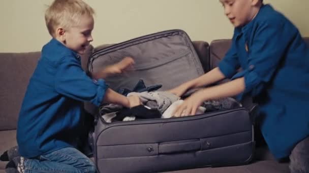 Vrolijke Jongens Een Valise Met Verschillende Kleren Bank Kamer Twee — Stockvideo