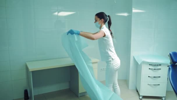 身穿白衣的年轻女护士在医院里摆放着蓝色的材料 戴面具的妇女为牙医办公室在室内工作做好准备 — 图库视频影像