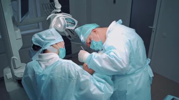 身穿蓝色军服的专科医生和女助手在牙科诊所工作 专业牙医和护士为病人的牙齿做手术 口头治疗 — 图库视频影像