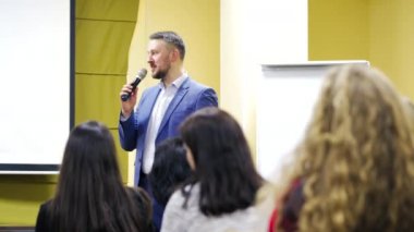 İdari lider halka açık seminerde mikrofona konuşuyor. Konferans sırasında seyirciye profesyonel konuşmacı öğretiyor.