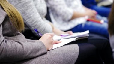 Genç çalışanlar içeride iş konferansında yazışıyorlar. Kadınlar iş toplantılarında çarşaflara not alıyorlar..