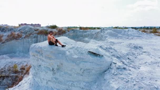 凶残强壮的健美健美运动员站在室外 在采石场拍照 户外运动的概念 空中风景 英俊的壮汉坐在采石场的最高峰上 白色的风景 — 图库视频影像