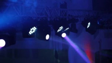 Renkli arka planda parlayan projektörün parlak ışıkları. Kulüpteki partide projektör lens ve beyaz duman..