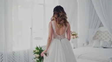 Işık stüdyosunda güzel bir modelin üzerindeki seksi dantelli gelinlik. Lüks elbiseli, çiçekli çekici gelin yatak odasındaki pencereye doğru geliyor..
