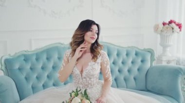 Kanepede eli boynundayken çok güzel bir genç kadın. Bir buket çiçekli gelinlik içindeki lüks gelin evde damadı bekliyor..
