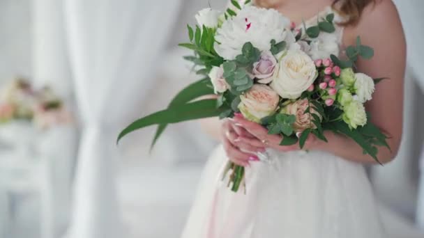 美しい花嫁の手の中にクリーミーなバラの結婚式の花束 白いウェディングドレスを着た素敵な若い女性が花を持っています — ストック動画