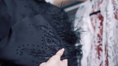 Atölyede tüyleri olan güzel siyah bir bez tutan kadın elleri. İçerideki profesyonel bir terzinin elinde siyah kumaşın şık bir parçası. Moda, terzilik, dükkan konsepti..