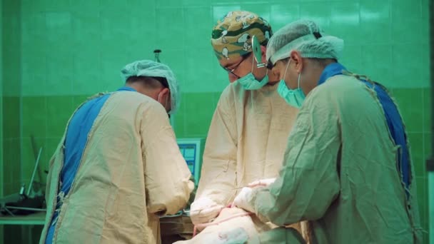 外科医生在两名专家的帮助下 使用无菌仪器进行手术 由专业外科医生组成的小组在医院手术室为病人做手术 医生在室内使用医疗设备 — 图库视频影像