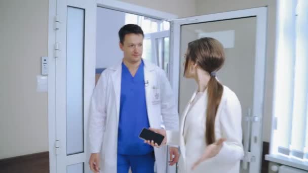 两个穿着军服的同事正在医院里讨论一些事情 男医生和女医生走进电梯时 在诊所里一起走着 一起交谈着 — 图库视频影像