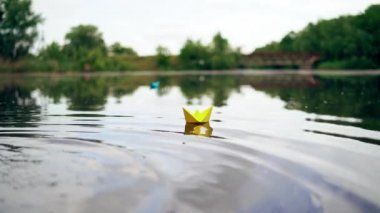 Nehirde dalgalar üzerinde yüzen kağıt bir gemi. Origami Kağıt Teknesi