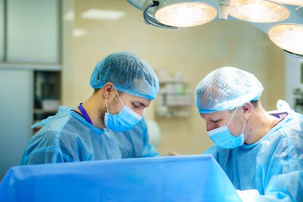 Medical team performing surgical operation in bright modern surgery room. Operating theatre. Modern equipment in clinic. Emergency room.