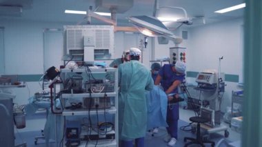 Tıbbi giysiler içindeki cerrahların ekip çalışması klinikte bir operasyon gerçekleştiriyor. Modern tıbbi ekipmanların arka planında ameliyat sırasında uzmanlarla birlikte ameliyathane..