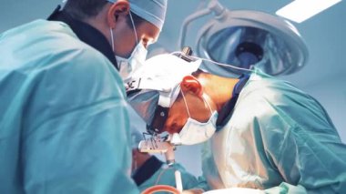 Tıbbi üniforma uzmanları hastanede bir operasyon yapıyorlar. Kafasında büyüteç olan cerrah ameliyathanede asistanlarla çalışıyor. Doktorun konsepti.
