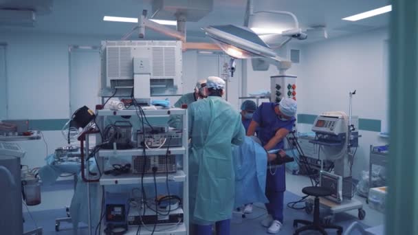 穿着医疗服装的外科医生的团队合作在诊所进行手术 在现代医疗设备的背景下 在行动期间配备专家的手术室 — 图库视频影像