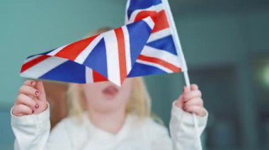 Sınıfta meyvelerin yerleşimiyle masada İngilizce öğrenen çocuklar. İngiliz bayrağını tutan ve eğitim merkezinin arka planında sallayan küçük kız..