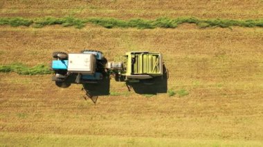 Traktörün sahada yeşil bir balya yaptığı en üst görüntü. Tarım makineleri çimenleri sıkıştırıyor ve hayvanlar için açık havada yuvarlak balyalar oluşturuyorlar..