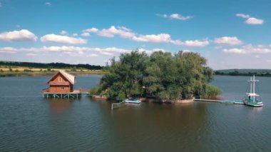 Yeşil ada ve deniz kenarında bir ev. Gölün ortasındaki güzel adanın doğal arka planda suyla çevrili havadan görünüşü..