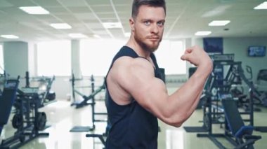 Spor kulübündeki adamın koluna yakın çekim kasları. Spor giyim sektöründe güçlü vücut geliştirici. Spor salonunda pazılarını gösteriyor..