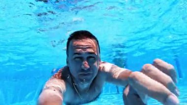 Adam havuzda su altında yüzüyor. Mavi berrak su ve su altında yüzen bir erkek. Suda yaz tatili.
