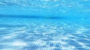 Yüzey dalgaları ile su altında boş yüzme havuzu. Havuzun dibinde, arka planda mavi berrak suyun içinde..