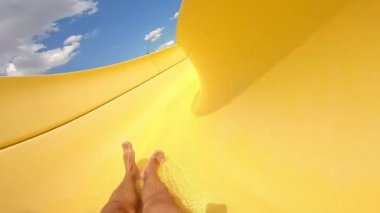 Yaz günü su kaydırağında eğlen. Adam su kaydırağından su parkındaki yüzme havuzuna düşüyor. Borunun içinde hızlı bir yol..