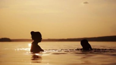 Anne oğluyla suda mutlu vakit geçiriyor. Nehirde yüzen neşeli çocuk ve yazın akşamları bir kadın onu kaldırıyor..