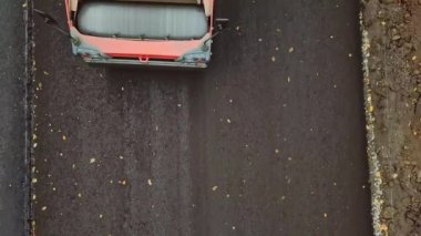 Yeni asfalta basan paten makinesinin yakın çekimi. Siyah asfalt döşeyen bir buharlı silindirin dönen tekerleğinin en üst görüntüsü. Drone görünümü.