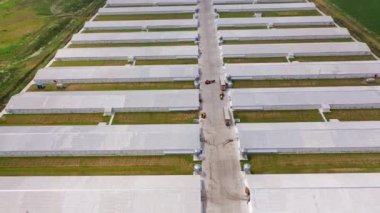 Güneşli bir günde modern çiftlik evlerinin insansız hava aracı görüntüsü. Açık havada iki sıra halinde bulunan yeni binaların hava görüntüsü. Kamera geri gider.
