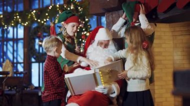 Çocuklar ve elfler Noel Baba 'nın beyaz sakalına ve kırmızı şapkasına dokunur. Noel Baba albümle oturuyor ve içeride iki küçük çocuk ve peri elfiyle eğleniyor..