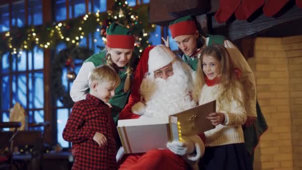 Dzieci Elfy Święty Mikołaj Albumem Mikołaj Trzyma Album Zdjęciami Elfy — Wideo stockowe