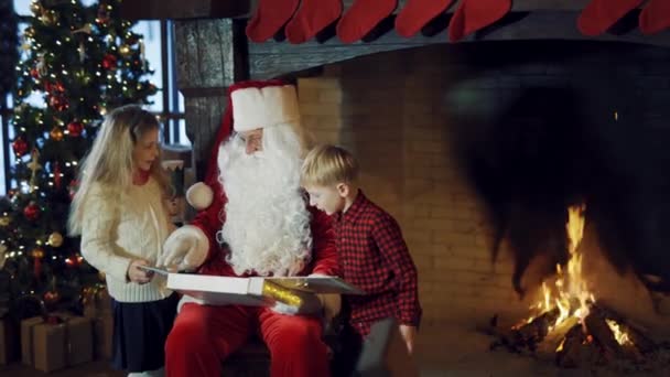 Веселые Дети Санта Клаусом Рядом Елкой Камином Санта Держит Большой — стоковое видео