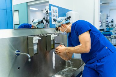 Cerrah ameliyat yapmadan önce ellerini iyice yıkıyor. Doktorlar ameliyattan önce ellerini yıkıyorlar.