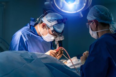 Ameliyathane ve ameliyat devam ediyor. Tıbbi ekip, parlak modern ameliyathanede cerrahi operasyon gerçekleştiriyor.