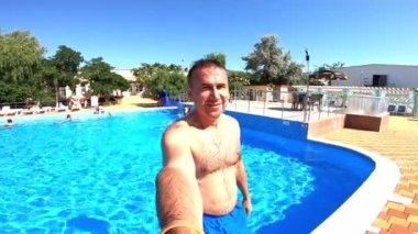 Yazın insanlar açık havada suya düşüyorlar. Yüzme havuzu geçmişi ve elinde kamerayla suya düşen bir adam. Yaz tatili.