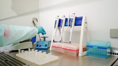 Kadın bilim adamı, laboratuardaki bir santrifüje birkaç şişe sıvı yüklüyor.. 
