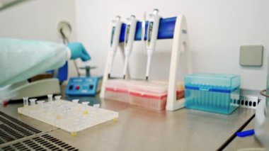 Kadın bilim adamı, laboratuardaki bir santrifüje birkaç şişe sıvı yüklüyor.. 