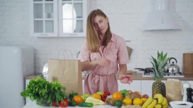 Genç bir kadın evde yemek yaparken mutfakta eğleniyor.