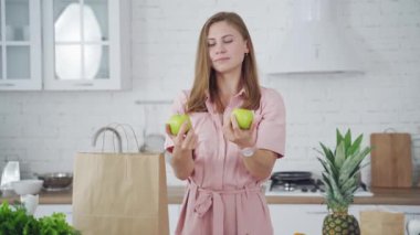 Genç bir kadın evde yemek yaparken mutfakta eğleniyor.