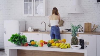 Genç bir kadın evde yemek yaparken mutfakta eğleniyor.