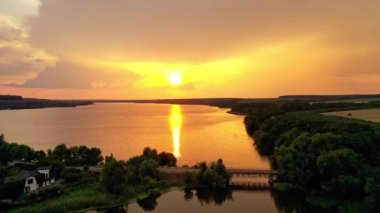 Gün batımında nehrin üzerindeki altın yolun inanılmaz manzarası. Akşamları doğanın muhteşem manzarası. Hava görüntüsü. Kamera ileri gider.