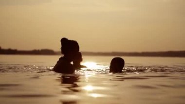Çocukların silueti yaz mevsiminde anneleriyle birlikte suyun içinde harika vakit geçiriyorlar..