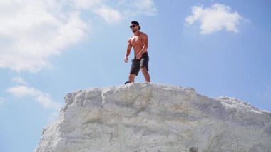 Beyaz tenli ciddi vücut geliştirici dağda açık havada eğitim görüyor.