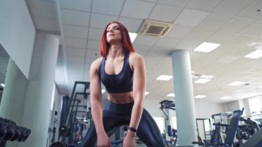 Kas kızıl saçlı, ağır kettlebell 'li bir kadın. Atletik vücutlu bir kadın spor merkezinde kaslarını çalıştırmak için ağırlık kaldırıyor..