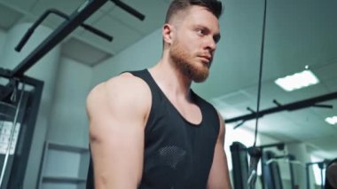 Spor kulübünde kol pazılarını çalıştıran konsantre bir sporcu. Genç sporcunun portresi halatı çekerek modern bir simülatörde çalışıyor..
