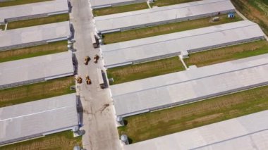 Kümes hayvanları için modern binaların çatılarının en üst görüntüsü. Açık havada tarım için çağdaş bir alan. Kırsaldaki iki sıra uzun çiftlik ahırının havadan görünüşü.