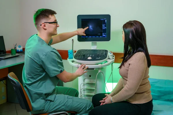 一位年轻的男医生给病人看腹腔超声检查 医生给一个女人做了分析 带特殊装备的快乐男性医生 — 图库照片