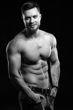 Kaslı ve seksi bir adam. Mükemmel karın kasları olan genç adamın çıplak gövdesi. Siyah ve beyaz. Yarısı kameraya döndü. Yakın çekim..
