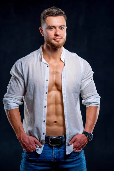 Hafif bir gülümsemesi olan mutlu genç bir adamın portresi. Beyaz gömlek, koyu arka planda izole edilmiş. İnsan kaslı vücudu.