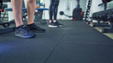 Spor salonunun zemininde bir erkek ve kadının spor ayakkabıları. Dambıllar bir erkek ve bir kadın tarafından eğitildikten sonra yere konur. Yakın plan..